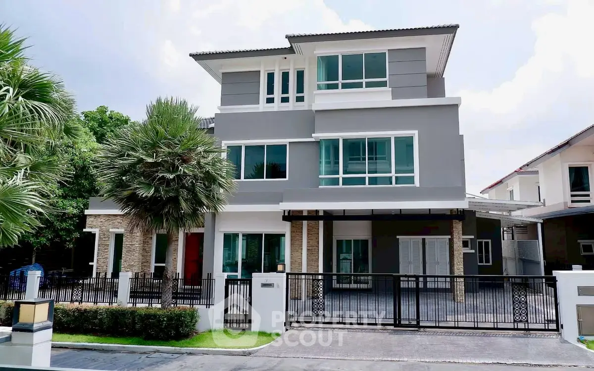 Modern three-story house with sleek design and spacious driveway in a suburban neighborhood.
