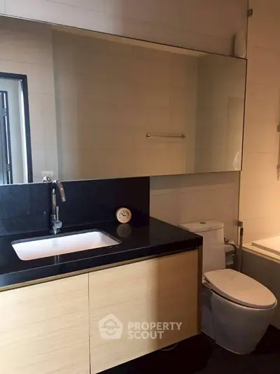 Modern bathroom with sleek black countertop and large mirror