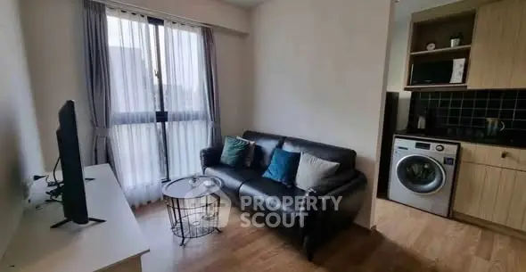 Cozy living room with modern sofa and in-unit washing machine, perfect for urban living.