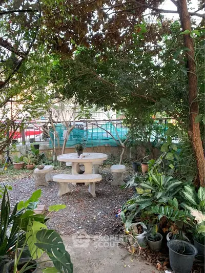 Charming garden with stone seating surrounded by lush greenery, perfect for relaxation.