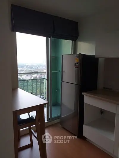 Modern kitchen with balcony view and sleek fridge in high-rise apartment.