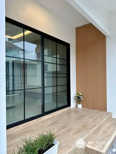 Modern entrance with sleek glass doors and wooden accents, perfect for contemporary homes.