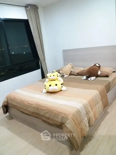 Cozy bedroom with plush toys and large window offering city view