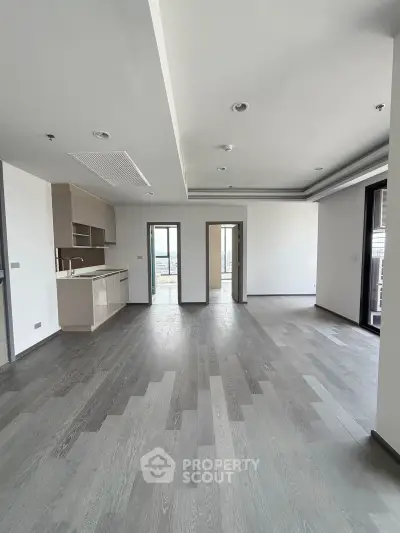Spacious modern living room with open kitchen and elegant flooring in a luxury apartment.