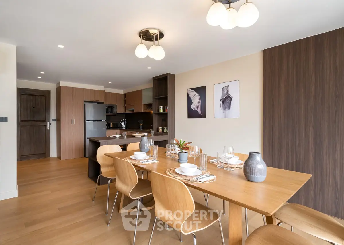 Modern dining area with elegant wooden table and chairs, open kitchen layout, and stylish decor.