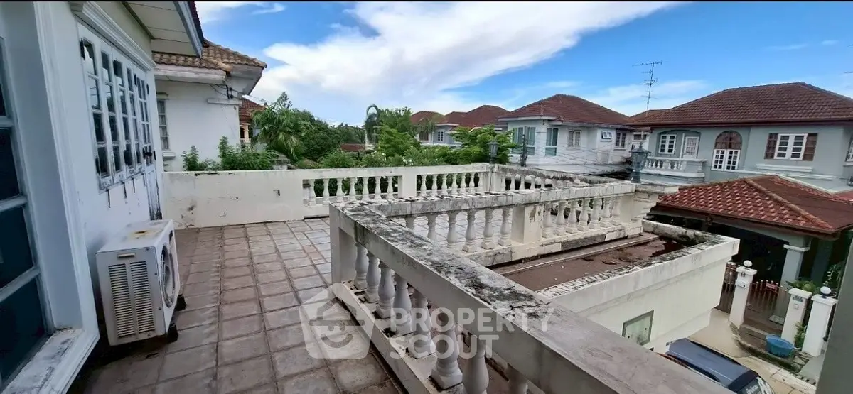 Spacious balcony with scenic neighborhood view and classic railing design.