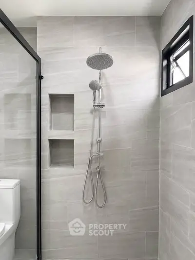 Modern bathroom with sleek shower and neutral tiles, featuring a minimalist design and natural light.