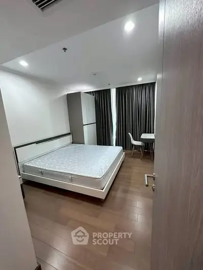 Modern bedroom with wooden flooring and large windows for natural light