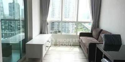 Bright modern living room with large windows and city view, featuring a cozy sofa and sleek furniture.