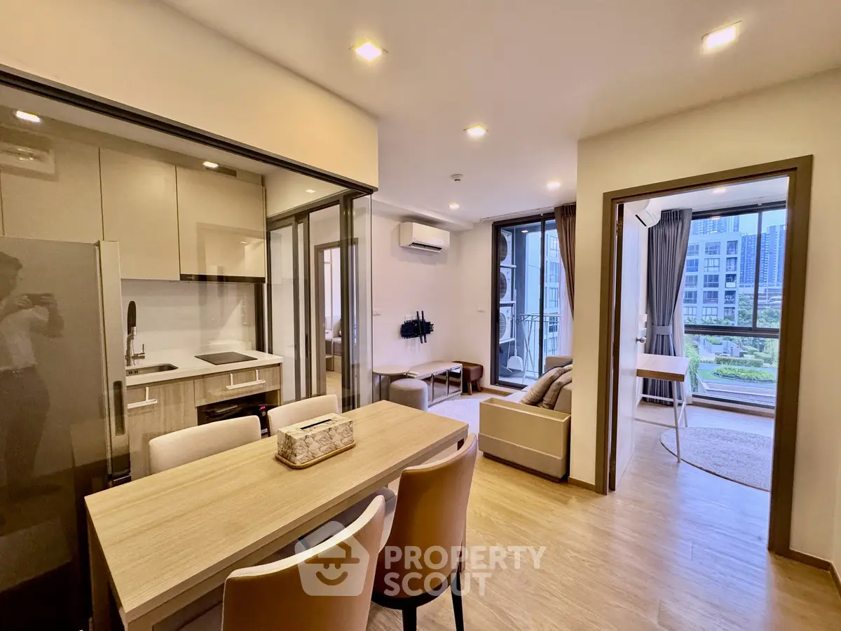 Modern open-plan living room with kitchen and balcony view in a stylish apartment.