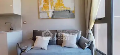 Modern living room with cozy gray sofa and abstract art, featuring large window for natural light.
