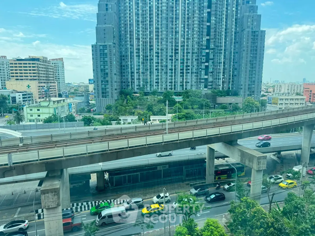 Stunning urban view of modern high-rise building with busy highway and lush greenery.