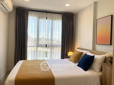 Cozy bedroom with modern decor and large window offering natural light.