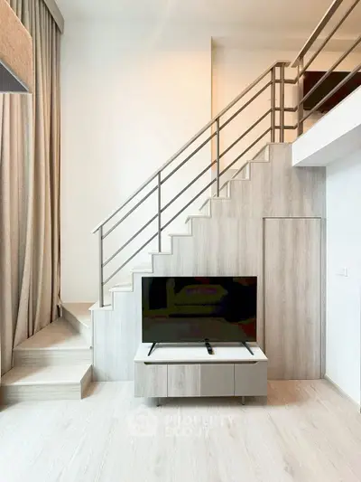 Modern living room with stylish staircase and sleek TV setup in a contemporary apartment.