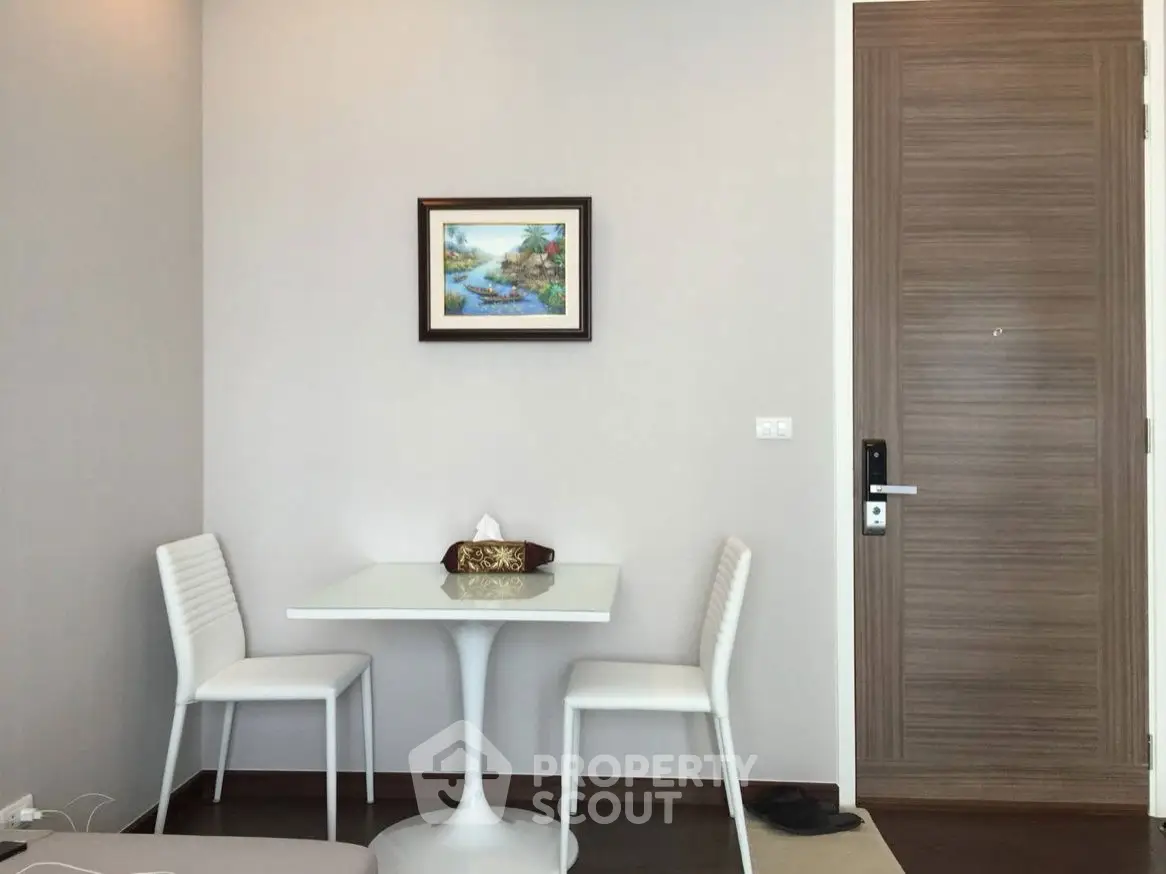 Modern minimalist dining area with sleek white chairs and table, perfect for compact spaces.