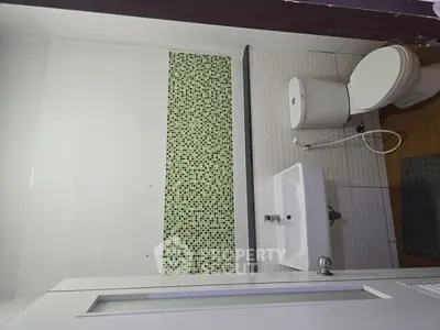 Modern bathroom with green mosaic tiles and white fixtures