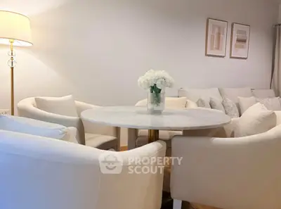Elegant living room with round marble table and plush white chairs, perfect for cozy gatherings.