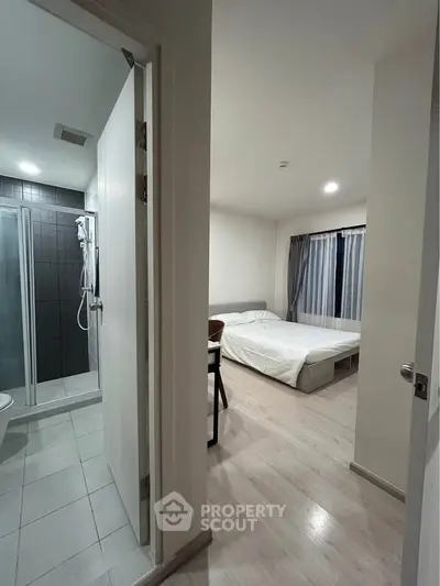 Modern apartment interior with bedroom and bathroom, featuring sleek design and natural lighting.