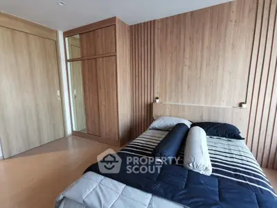 Modern bedroom with wooden accents and stylish bedding in a contemporary apartment.