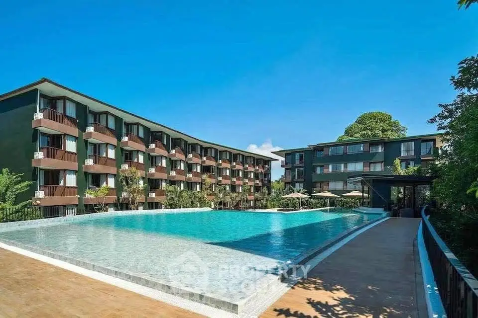 Luxurious apartment complex with stunning pool and modern architecture under clear blue sky.