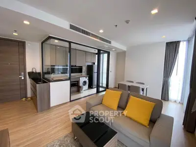 Modern open-plan living room with kitchen, featuring sleek design and bright natural light.