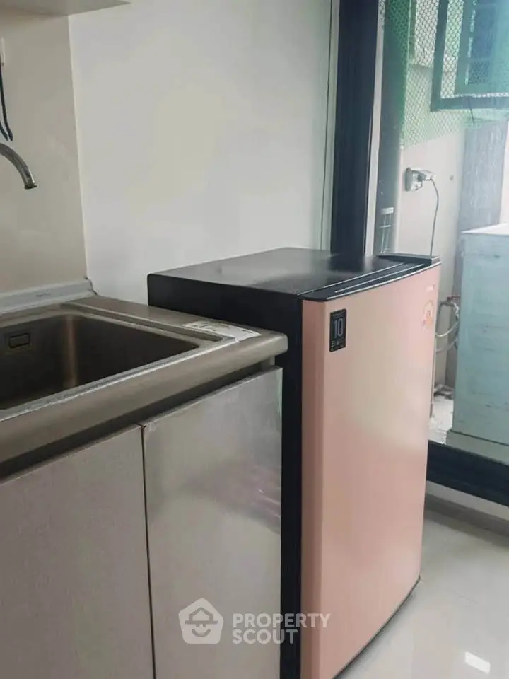 Compact kitchen area with modern sink and sleek mini fridge, perfect for urban living.