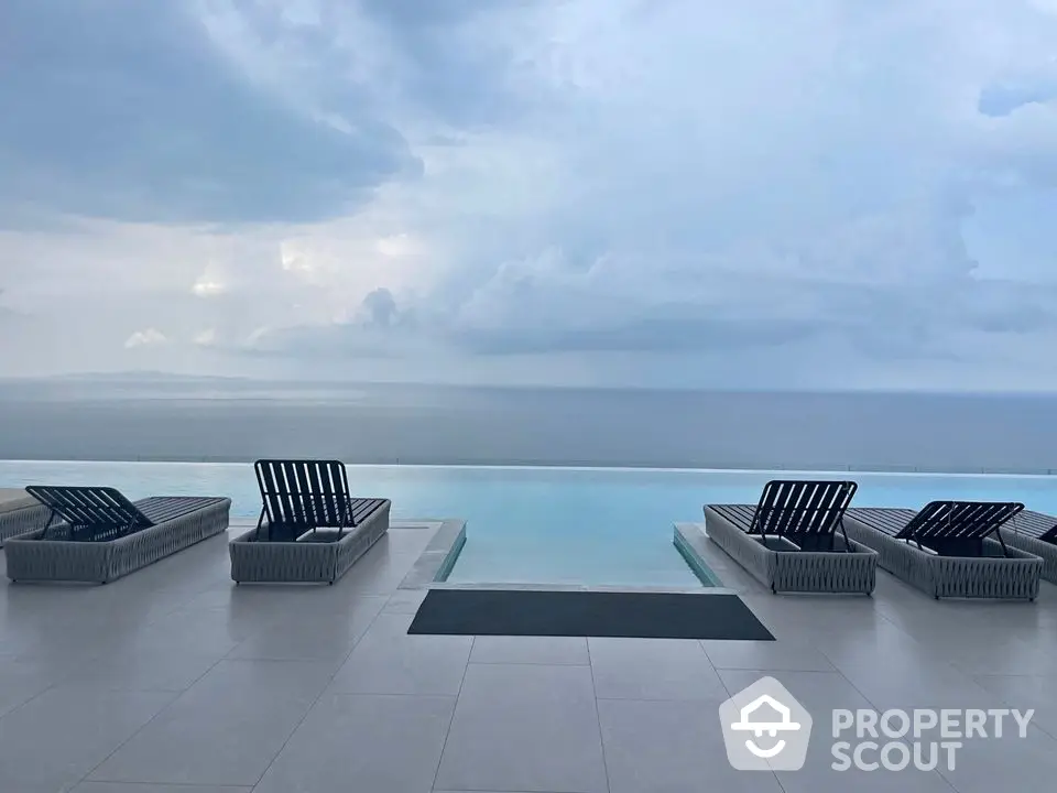 Luxurious infinity pool with ocean view and elegant lounge chairs under a serene sky.