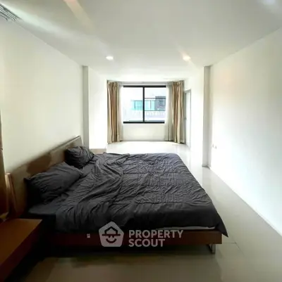 Spacious bedroom with modern design and large window offering natural light.