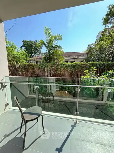 Charming balcony with glass railing and garden view, perfect for relaxation.