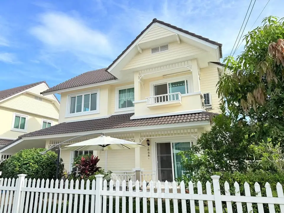 Charming two-story house with white picket fence and lush garden, perfect for family living.