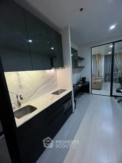 Modern kitchen with sleek black cabinets and marble backsplash in stylish apartment