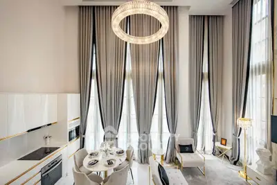 Luxurious high-ceiling living room with elegant decor and modern kitchen in open layout.