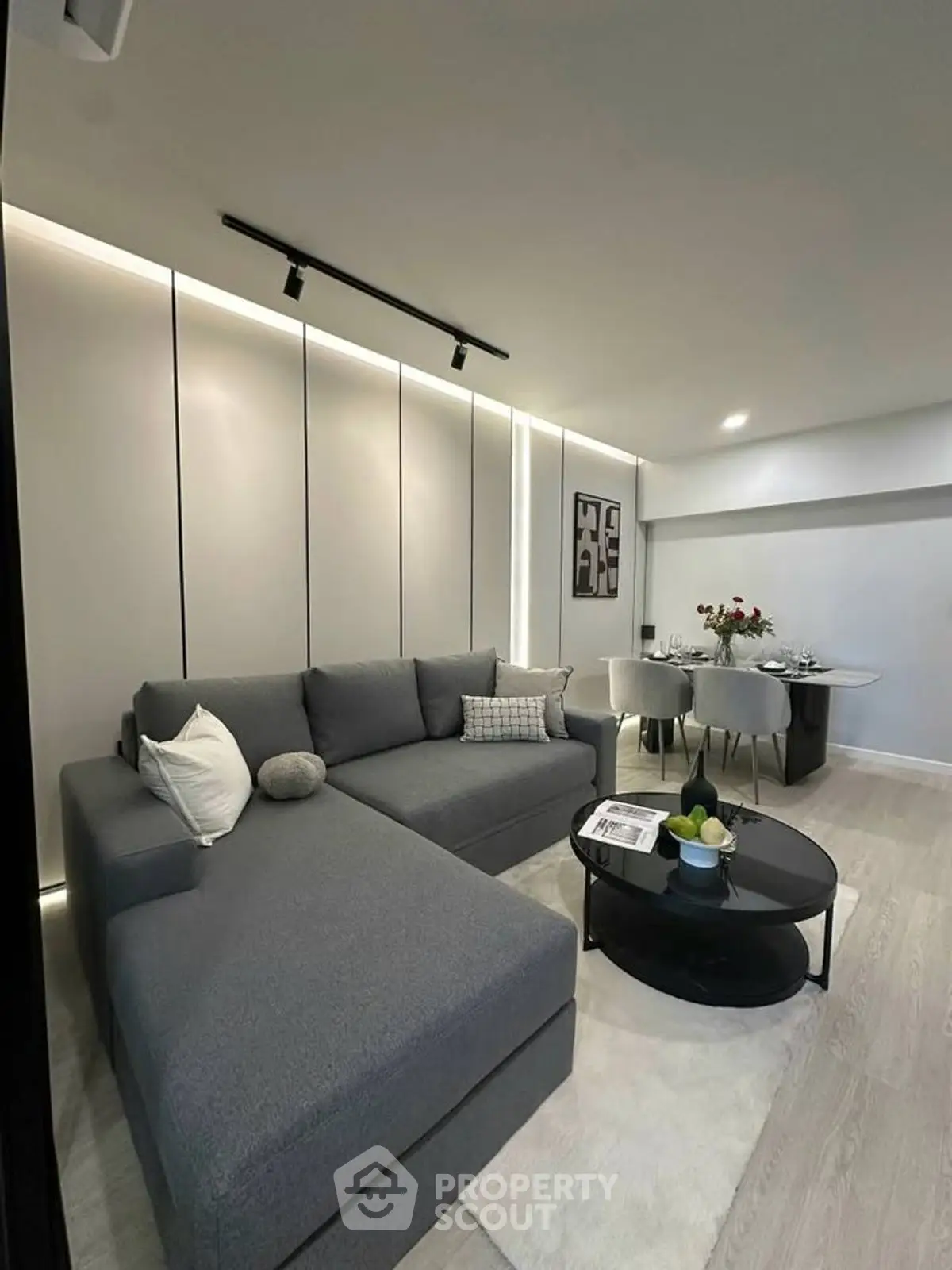 Modern living room with sleek gray sectional sofa and elegant dining area