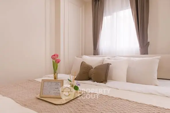 Elegant bedroom with cozy decor and soft lighting, featuring plush pillows and a stylish tray with flowers.
