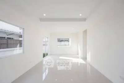 Spacious and bright living room with large windows and glossy tiled floors in modern home.
