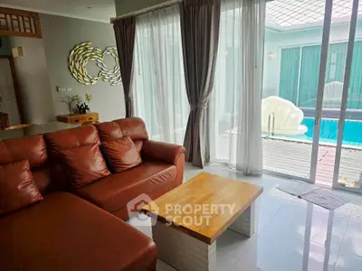 Luxurious living room with pool view, featuring elegant leather sofa and modern decor.