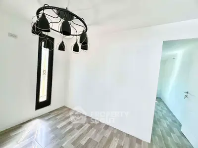 Minimalist room with modern chandelier and wooden flooring