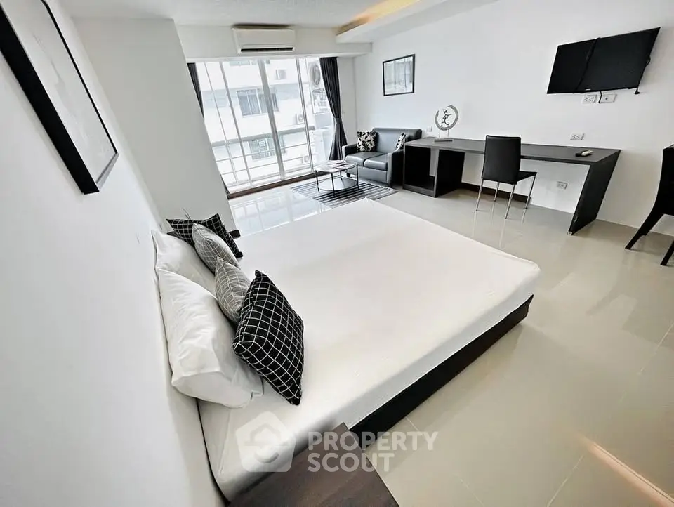 Modern studio apartment with sleek furnishings and large windows for natural light.