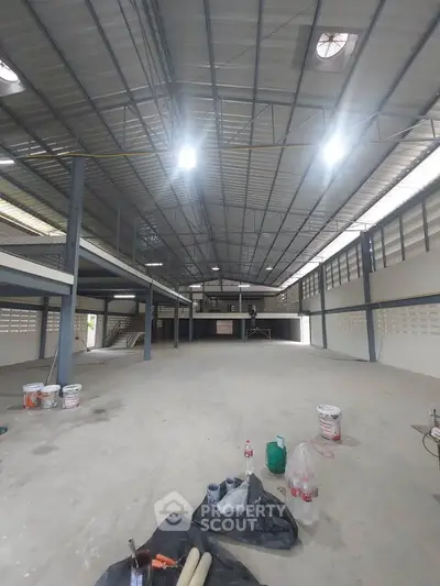 Spacious industrial warehouse with high ceilings and ample natural light, perfect for storage or manufacturing.