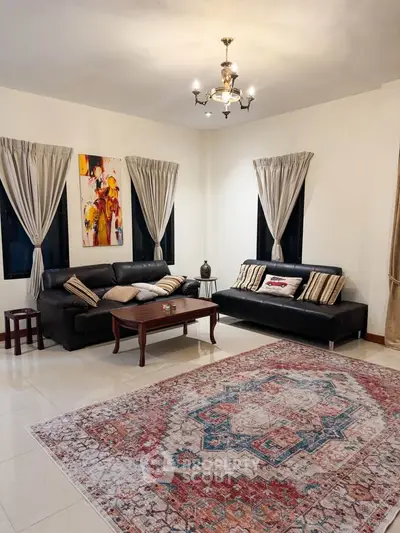 Elegant living room with stylish decor, featuring black leather sofas, a colorful rug, and modern artwork.