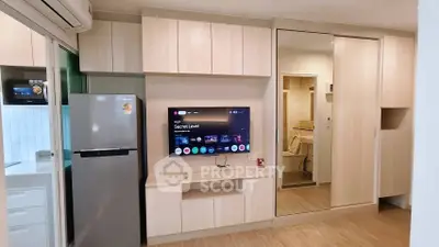 Modern living room with sleek cabinetry and integrated TV, adjacent to a compact kitchen.