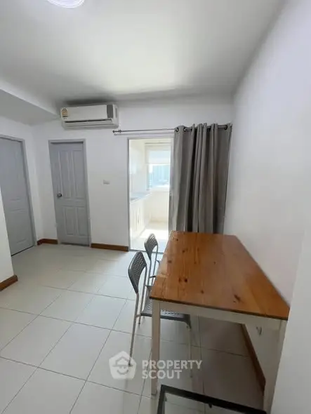Bright dining area with wooden table and chairs, adjacent to a modern kitchen.