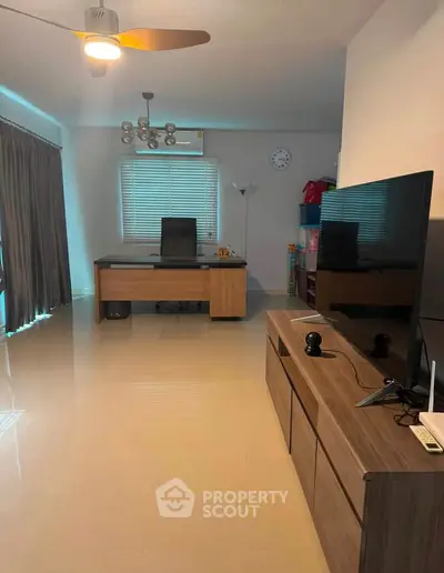 Spacious home office with modern desk and entertainment setup, ideal for productivity and relaxation.