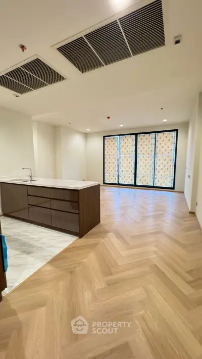 Spacious open-plan living room with modern kitchen and elegant flooring.
