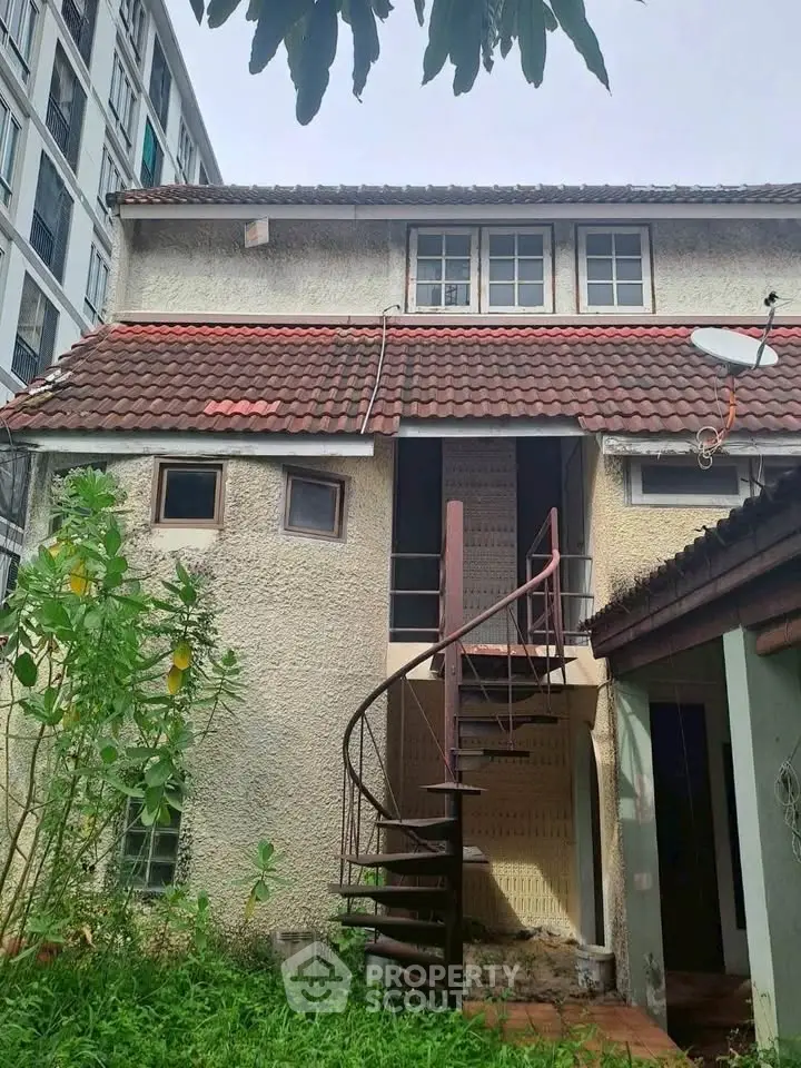 Charming vintage house with spiral staircase and red tiled roof, perfect for renovation.