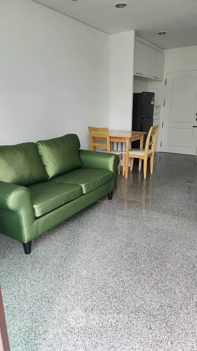 Spacious living room with green sofa and dining area in modern apartment