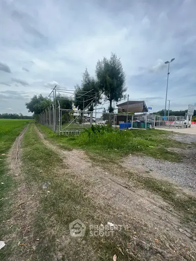Expansive land plot with potential for development, featuring lush greenery and clear skies.