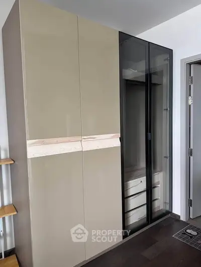 Modern wardrobe with glass doors and wooden accents in a stylish interior space.