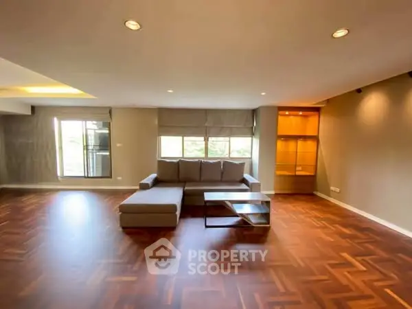 Spacious modern living room with elegant parquet flooring and cozy sectional sofa.
