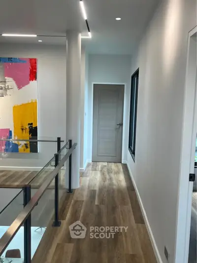 Modern hallway with wooden flooring and contemporary art in a stylish home interior.